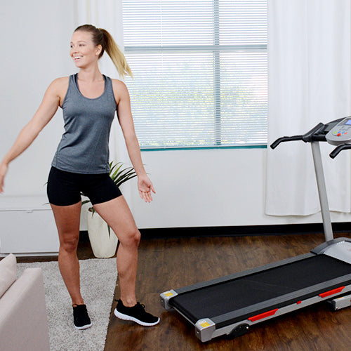 a woman stands beside a treadmill