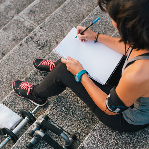 a person is writing exercising note to make workout routine sustainable
