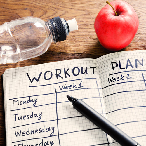 workout plan written in notebook next to water bottle and apple