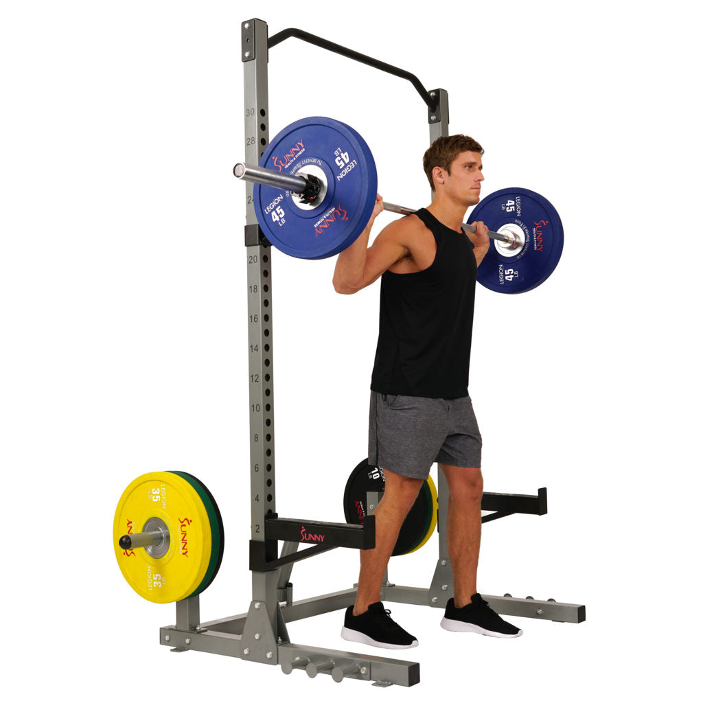 man holding barbell in front of squat rack