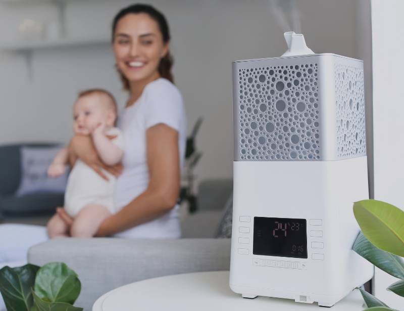 Woman carrying a baby next to a humidifier