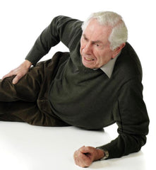 Elderly man laying on ground and falling and hurting his hip