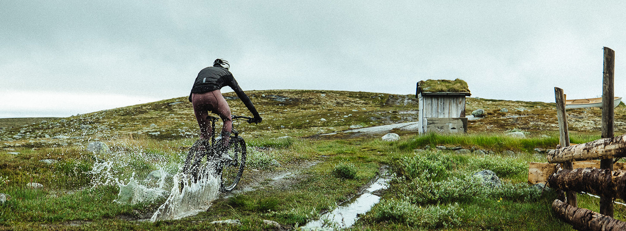 Cycliste traversant une flaque d'eau sur son vélo, protégé par sa veste. Exo et d'un cuissard Absolute