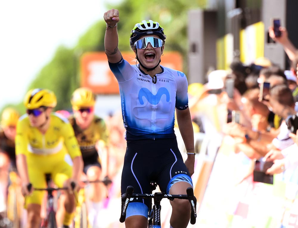 Emma Norsgaard entering the finish line with her fist in the air and a satisfied gesture, declaring herself the winner of the stage. 