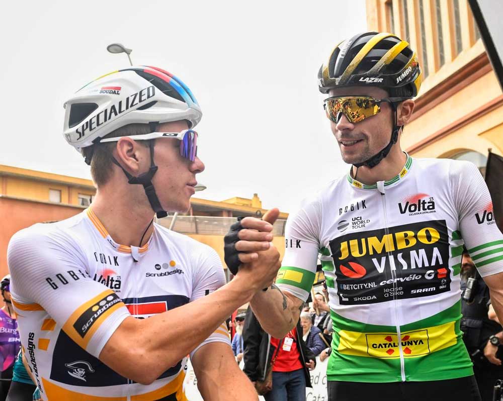 Roglic und Evenepoel grüßen einander, beide tragen das Trikot des Führenden in ihrer jeweiligen Wertung. Gobik. 