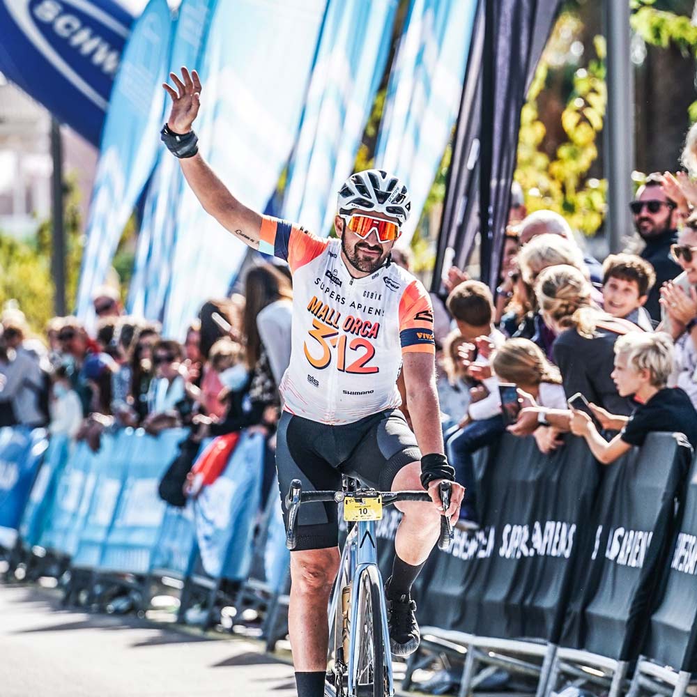 The well-known Spanish cyclist Alberto Contador enters the finish line of the 2022 edition of the Mallorca312. The athlete raises his fist as a sign of achievement and his face expresses satisfaction and gratitude with the public. 