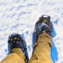 Load image into Gallery viewer, Birds eye view of a person wearing Outbound Lightweight Aluminum Frame Snowshoes in 21 inches on snow