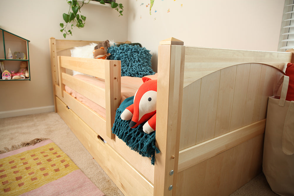 closeup of neutral toddler bed with guardrail light wood