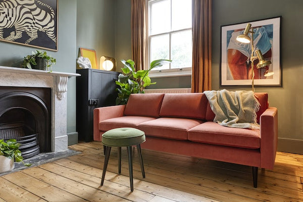 Brick sofa and green stool in corner of living room by fireplace