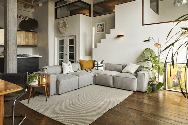 Grey L-shaped sofa demarcating living room from kitchenette