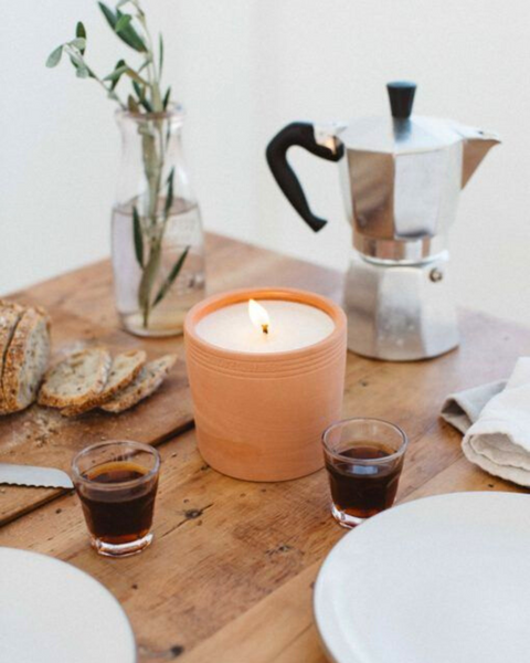 Candle in terracotta pot with coffee espresso on wooden table