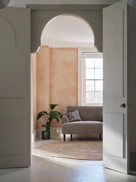 plaster pink wall with grey sofa