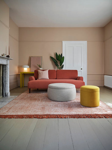 pink living room with red sofa and pink rug