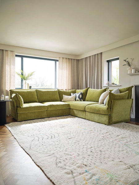 green corner sofa with curtains behind