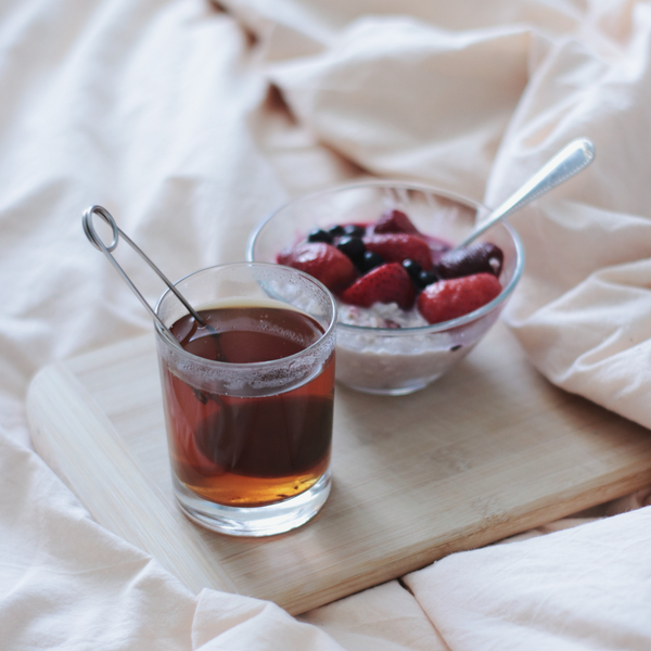 tea and breakfast bowl on tray in bed