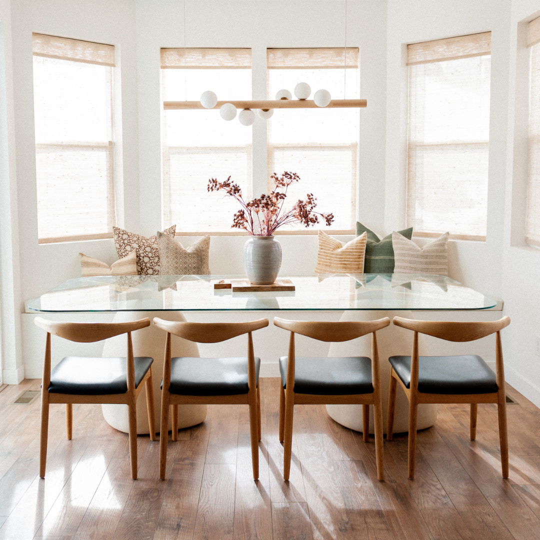 bright and airy dining room with window seating area filled with neutral color throw pillows