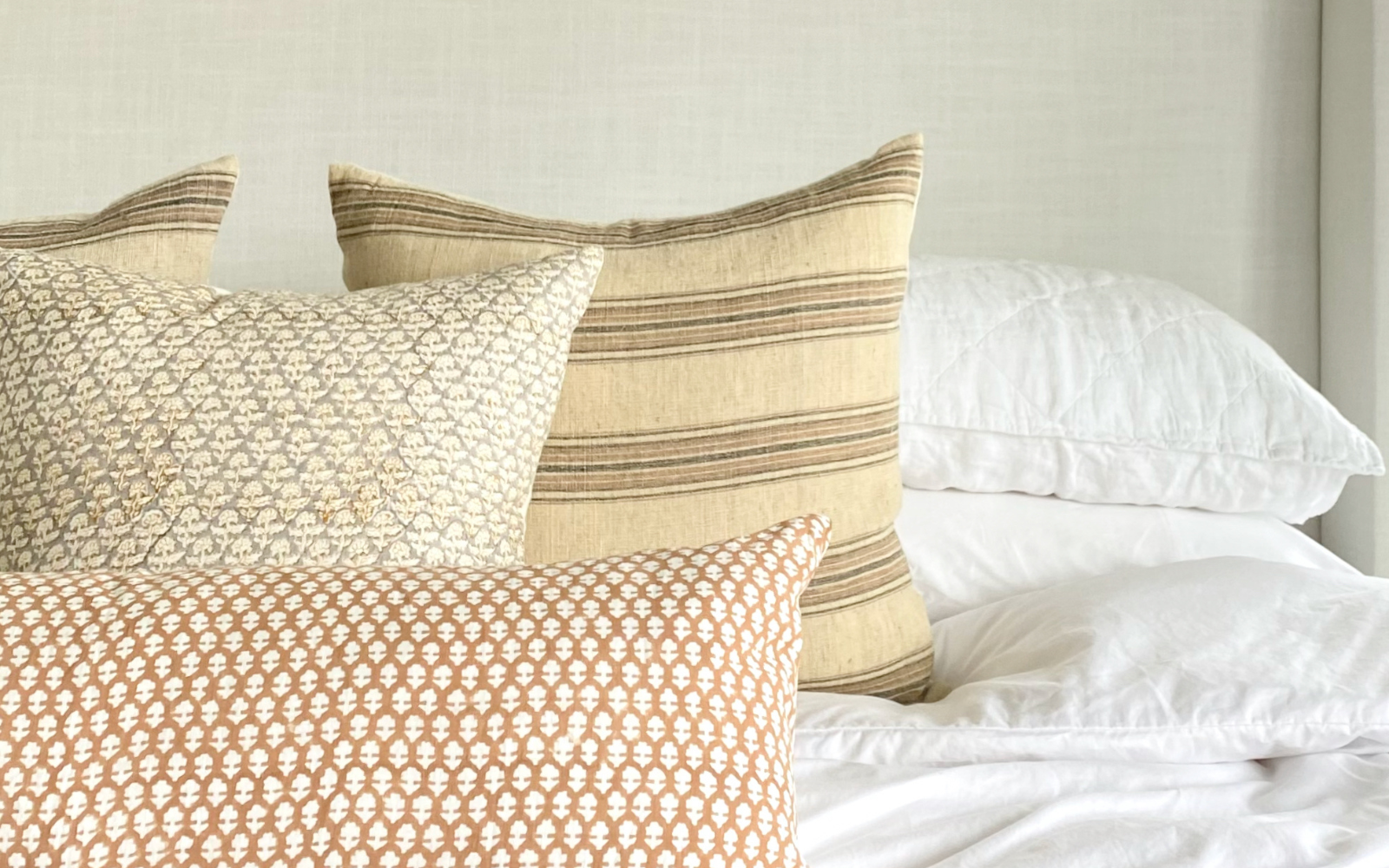 Neutral throw pillow arrangement on top of a white bed