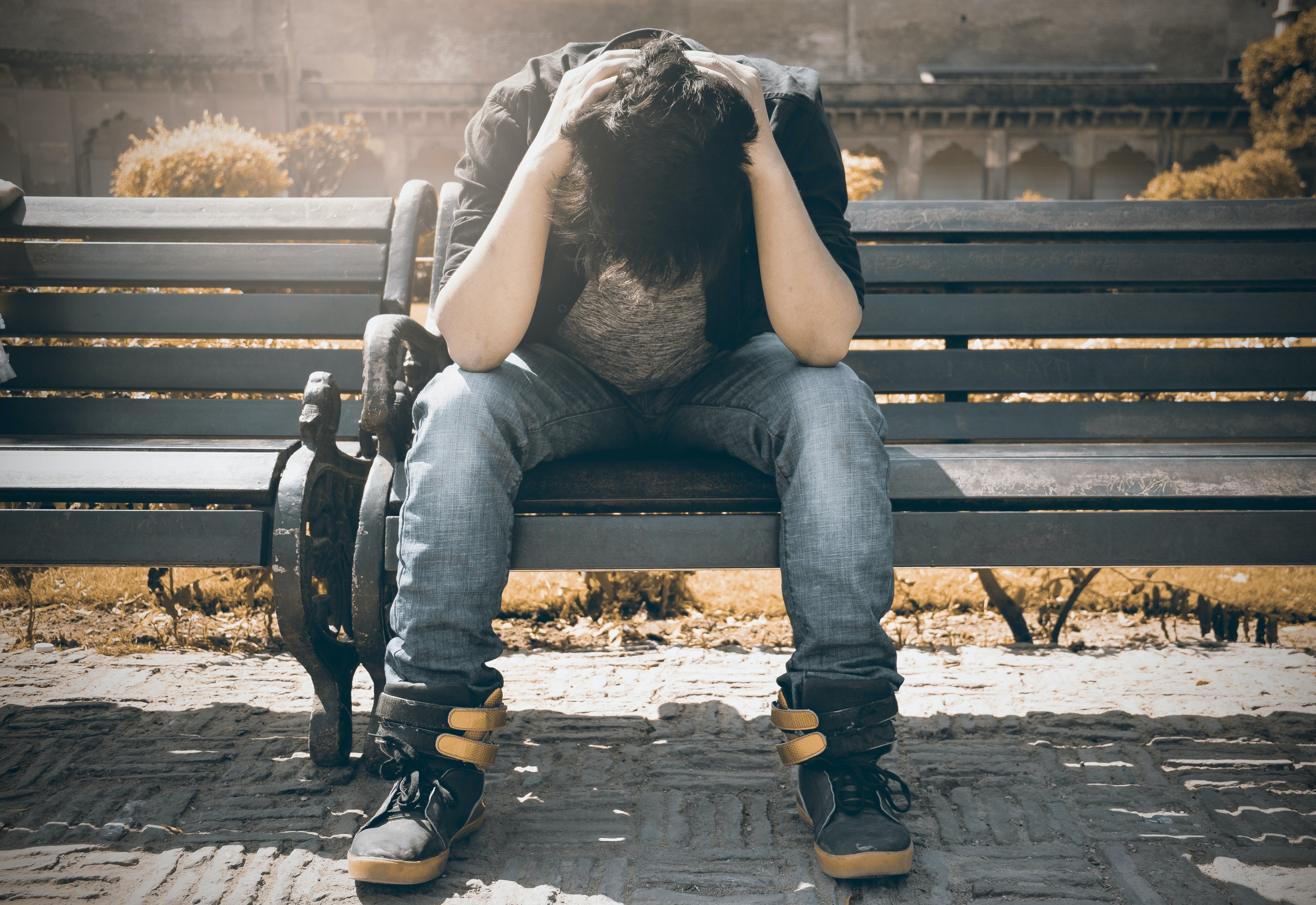 Distressed young man sitting on park bench.