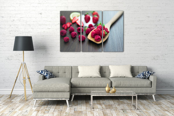 Leinwandbild Essensbilder Obst Früchte Himbeeren verteilt auf Holzlöffel und Tisch