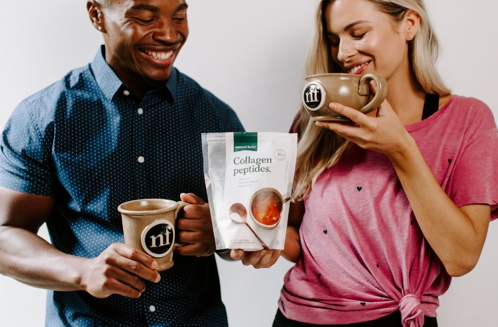 man and woman smiling holding handmade natural force mugs and a bag of natural force collagen peptides