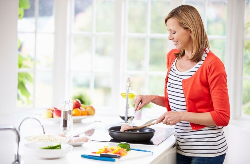 woman smiling while cooking with met oil in a skillet