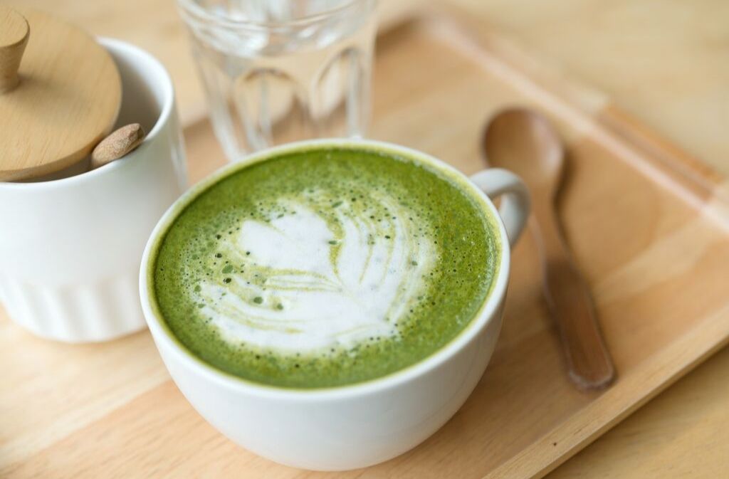 matcha latte in a white mug on a bamboo tray