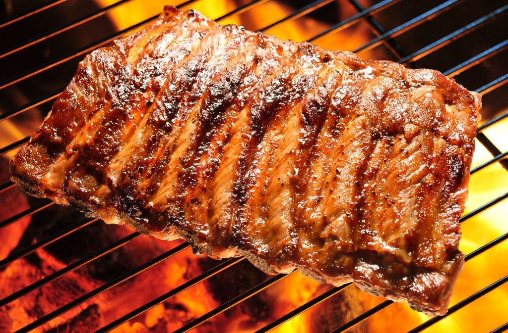 baby back ribs on a grill grate with flames beneath