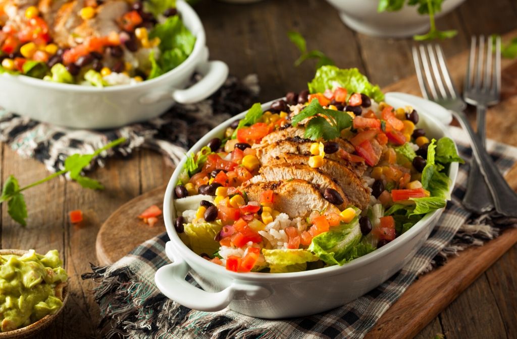 burrito bowl with chicken and vegetables on a checkered dish towel