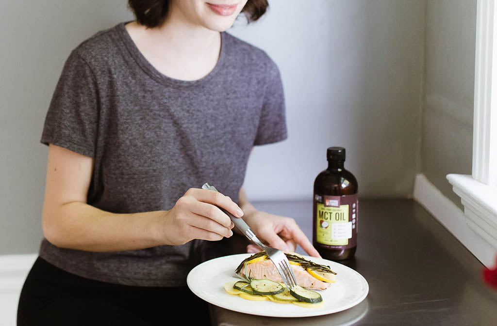 woman eating keto baked salmon and veggie packet