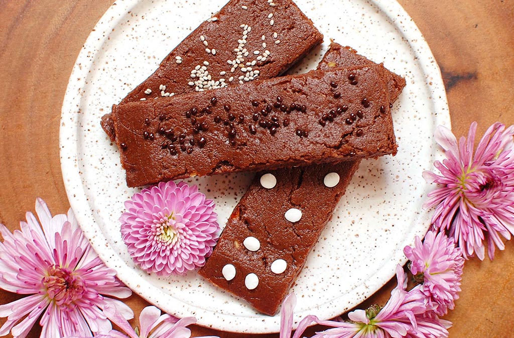 keto chocolate mint protein bars on a white circular plate surrounded by pink flowers
