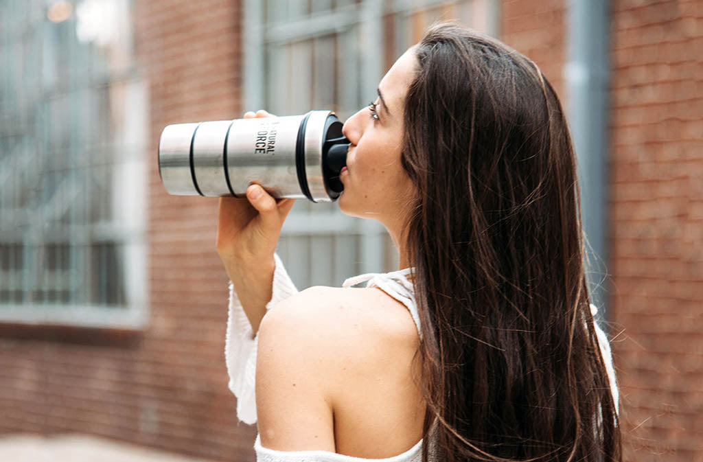 woman drinking from silver natural force blender bottle