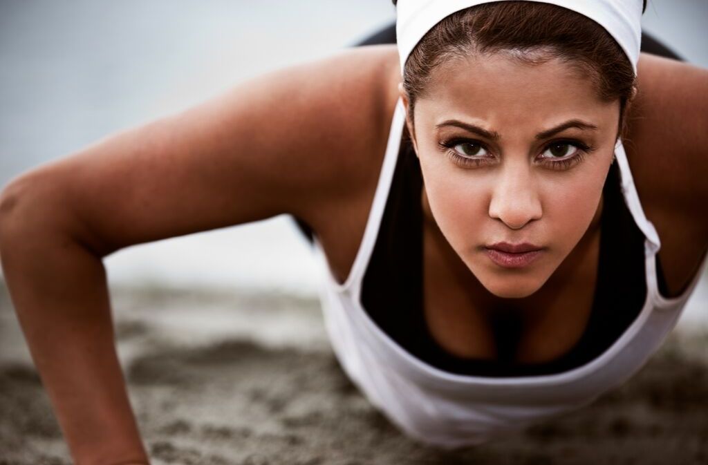 athletic woman doing a push up while staring seriously ahead