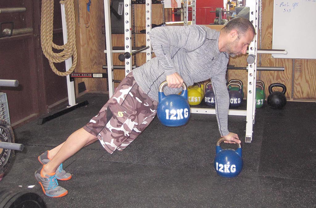 man doing a renegade row with kettlebells