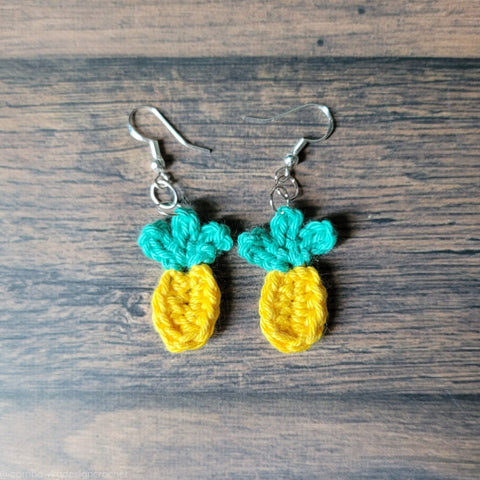 crochet earrings pattern free - crocheted pineapple earrings against a wooden background