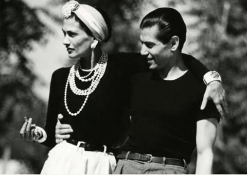 black and white image of man in black t shirt and woman in white twist knot headband and pearls