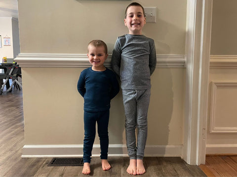 Two young boys standing against a wall with Ella's Wool base layers on