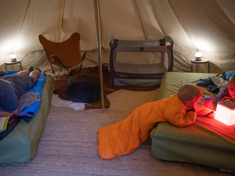 A man on an inflatable mattress and a young child wearing a Morrison Outdoors Big Mo sleeping bag inside a tent