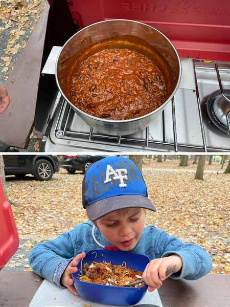 A pot of chili on a camp stove on top and a young boy eating the chili in a bowl at a picnic table outdoors on the bottom