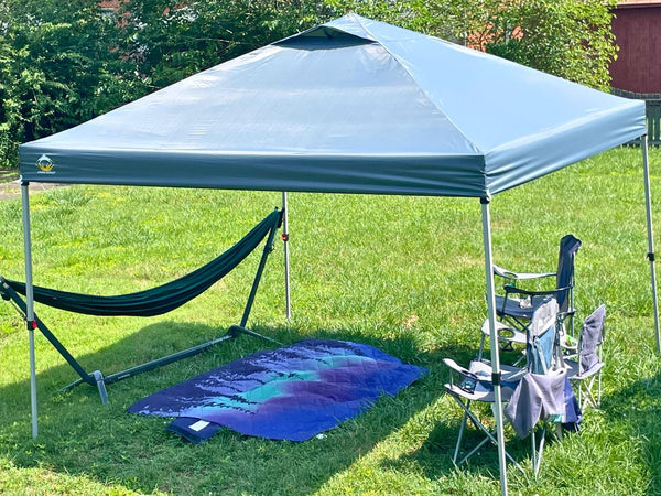 A Crown Shades Canopy set up to provide shade for a hammock and a blanket outdoors