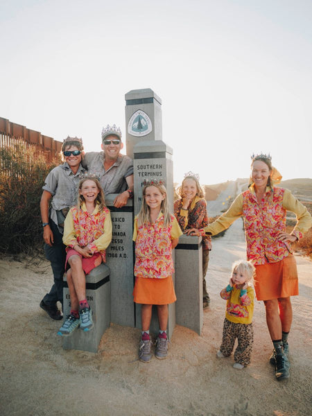 A family of seven standing in front of a summit marker along the Pacific Crest Trail