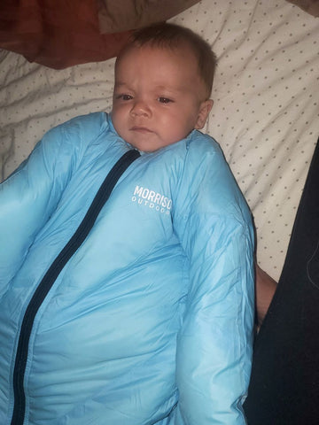 A sleepy baby wearing a Morrison Outdoors Little Mo sleeping bag
