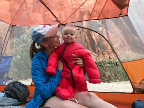 A baby wearing a Morrison Outdoors Little Mo 40 sleeping bag being held by a woman in a tent