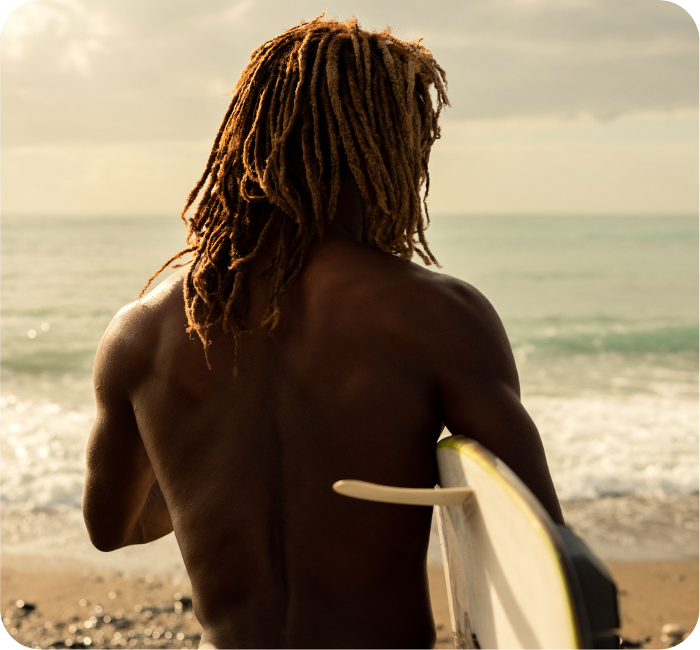Man facing ocean holding surf board