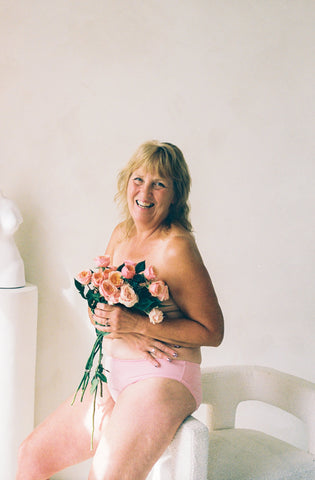 Joan smiles with flowers for Breast Cancer Awareness Month