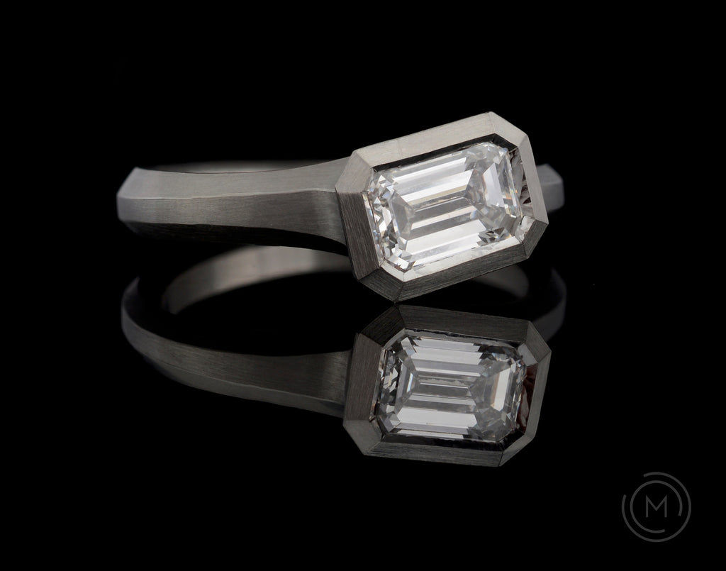 Modern hand-carved platinum engagement ring with emerald-cut white diamond