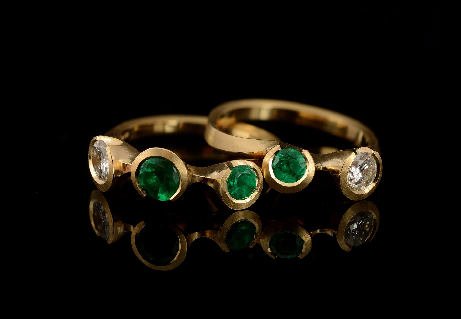 Pair of bespoke Arris carved yellow gold rings set with emeralds and diamonds
