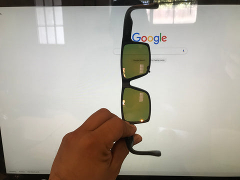 Polarized sunglasses with a Brownish tint being held vertically 