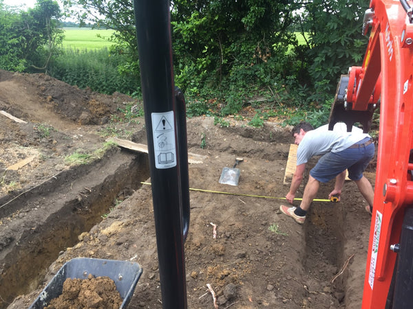 Myles measuring the ground to plan the foundations of the workshop