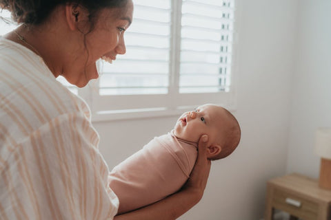 Mother smiling at baby who is content in BlankyDink Swaddle designed by BabyDink