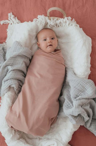 Newborn baby sleeping peacefully wrapped in a soft, organic cotton Babydink swaddle